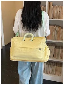 Vue de détail du grand sac de voyage jaune porté sur l'épaule à l'intérieur clairement.