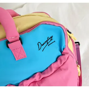 Nahaufnahme der farbblockierten Reisetasche mit einem lebendigen mehrfarbigen Design.
