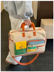 Detail shot of the color-block travel duffel bag showing front multi-pockets and handles.