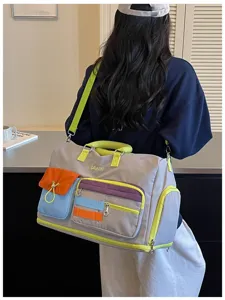 Color-blocking travel duffel bag detail, showing multi-pocket design and vibrant neon straps.
