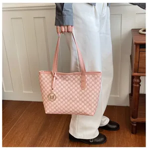 Nahaufnahme der rosa Shopper Tasche mit Monogramm-Muster und Metallanhänger in Hand.