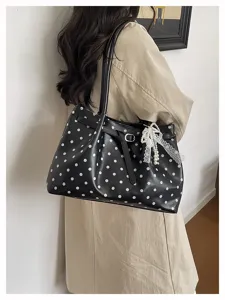 Vista dettagliata della borsa a spalla nera a pois con fiocco di perle e cinturino in pelle.
