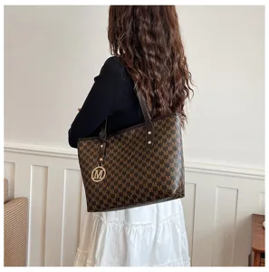 Detailaufnahme der braunen Monogramm Tote Tasche mit M Logo Anhänger für Damen Alltag.