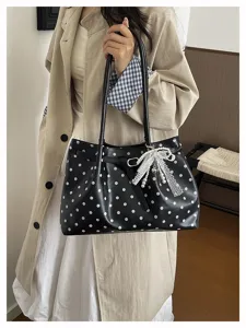 Vista dettagliata di una borsa nera a pois con elegante fiocco in pizzo e perle.