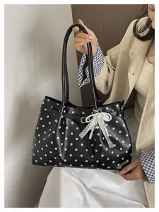 Vista dettagliata di una chic borsa nera a pois con ciondolo a fiocco in pizzo e perle da donna.