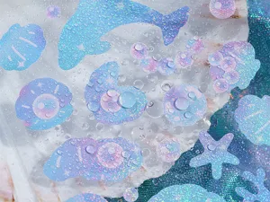Detailed close-up of marine theme holographic journal stickers with cute dolphin and shell designs.