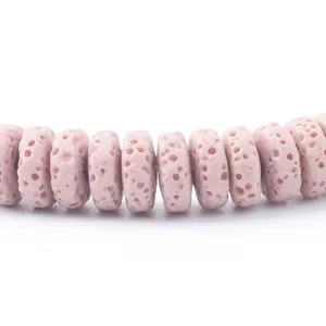 Primo piano di perline distanziatrici in pietra lavica porosa rosa con texture naturali.
