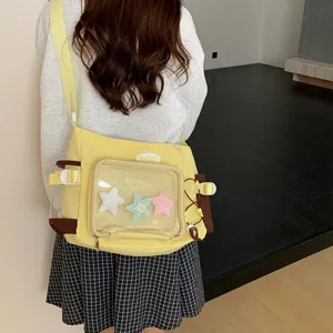 Detail view of the yellow canvas ita bag showing its clear pocket, plush stars, and straps.