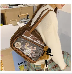 Detalle de bolso ita de felpa marrón con ventana transparente y colgante bonito.