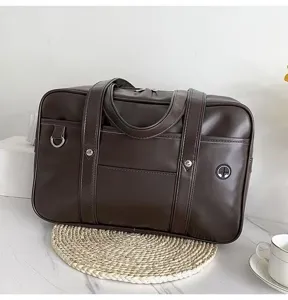 Dark brown PU leather JK uniform bag detail shot, featuring dual top handles, front pocket and D-ring.