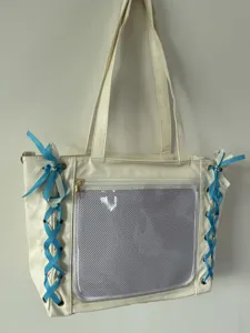 Detail view of white ita bag with blue ribbons and front clear mesh pocket for pins.