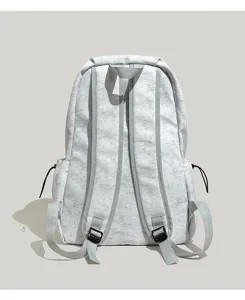 Detalle de mochila gris claro minimalista, bolso escolar de viaje diario informal con correas ajustables.
