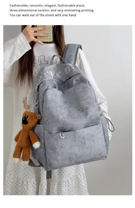 Mochila gris elegante de lona con gran capacidad, colgante de oso y diseño de estilo gótico.