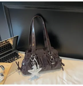 Detail shot of a dark brown patent leather shoulder bag with chic star pendant and pleats.