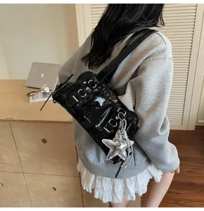 Detailed view of black patent leather shoulder bag with chic silver star keychain and hardware.