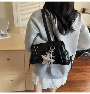 Detail shot of the black patent leather shoulder bag with star pendant, casual retro style.