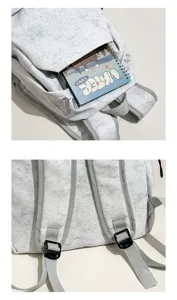 Detalle de mochila gris con tela suave, bolsillo frontal y hebillas de correa.