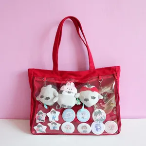 Red canvas ita bag detail showing transparent front pocket with cute anime plush toys and pins.