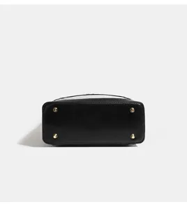Detailed bottom view of black doll bag, showing durable faux leather and metal feet.