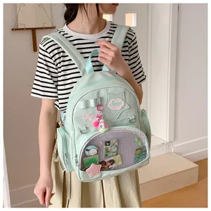 Vue détaillée du sac à dos Ita-bag vert pastel avec fenêtre transparente et écussons.