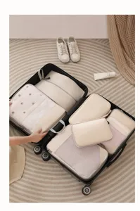Travel packing cubes set detail, beige mesh cosmetic bags organized neatly inside a open suitcase.