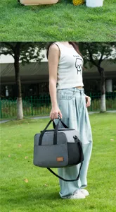 Close-up detail of a portable insulated lunch bag being carried outdoors on a green lawn.