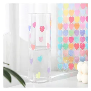 Clear glass tumbler cup with colorful heart patterns for daily drinking or desk decor.