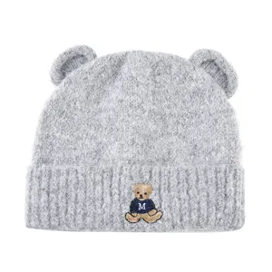 Detailed view of the cute grey knit beanie with bear ears and embroidered bear patch.