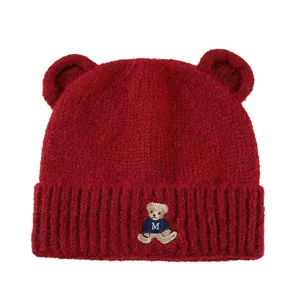 Close-up of wine red knitted beanie with cute bear ears and embroidered bear detail.