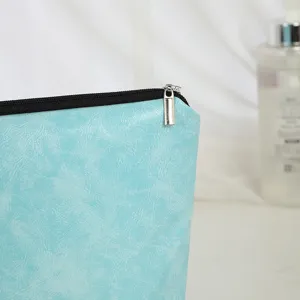 Detailed close-up of a light blue textured PU leather cosmetic bag with a black zipper and