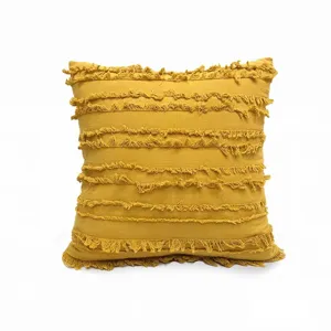 Boho style yellow throw pillow cover texture detail, striped fringe cushion close-up.