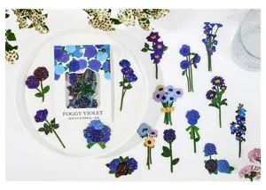 Detailed shot of blue floral PET stickers pack on white plate, featuring botanical stationery designs.