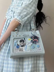Detailed view of the cute light blue ita bag with transparent window, custom anime pins and bow.