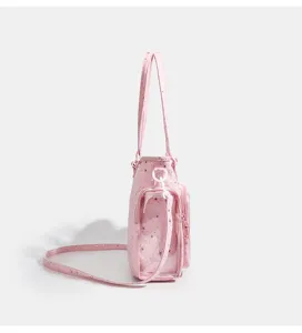 Side detail view of a pink star-patterned ita bag with transparent window and shoulder strap.