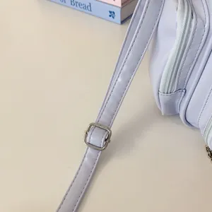 Detail shot of a light purple crossbody bag strap with metal buckle. Clean aesthetic design.
