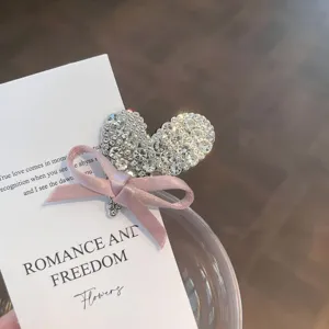 Detailed close-up view of sparkling rhinestone heart hair clip with pink ribbon bow.