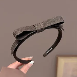 Gedetailleerde close-up van de elegante bruine stoffen strik haarband met zachte textuur.