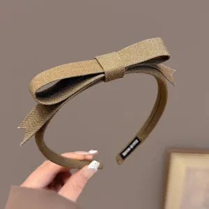 Detailopname van de bruine stoffen strikhaarband met fijne textuur en mooie strik.