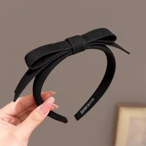 Gedetailleerd overzicht van de elegante zwarte stoffen haarband met strik en fijne afwerking.