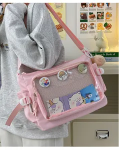 Detail view of pink itabag with clear window pocket, showing adjustable strap and badge display.