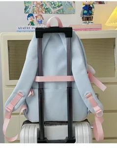 Mignon sac à dos d'étudiant bleu clair avec bretelles roses et sangle de valise.