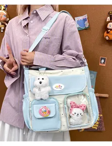 Detailed shot of the cute color-block shoulder bag with transparent pocket and plush pendants.