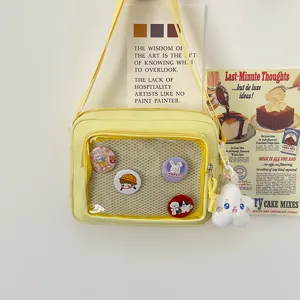 Yellow canvas ita bag with clear window, cute pins and plush cloud pendant detail view.