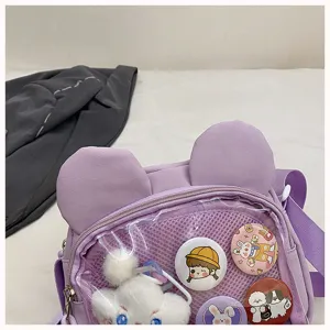 Nahaufnahme des lila Ita-Umhängetaschendetails mit Bärenohren und transparenter Tasche.