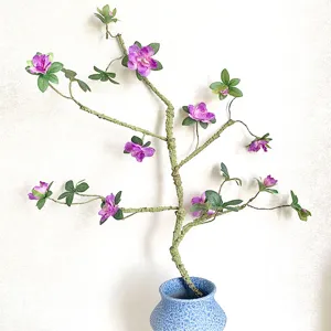 Artificial azalea flower branch with faux stem in blue ceramic vase for home zen decor.