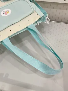 Detail view of the canvas shoulder tote bag featuring blue and white polka dots and durable straps.