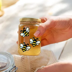 Nahaufnahme von Hologramm süßen Bienensticker auf Glasglas, schimmerndes glänzendes Detail.