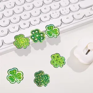 Gros plan de détail des autocollants trèfle vert holographique sur un bureau blanc et propre.