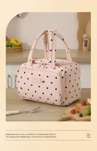 Detailed view of pink insulated lunch bag with stylish black polka dots and convenient handles.