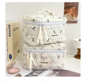 Trousse de maquillage matelassée avec motif nœud et pois, design vanity case double couche élégant.
